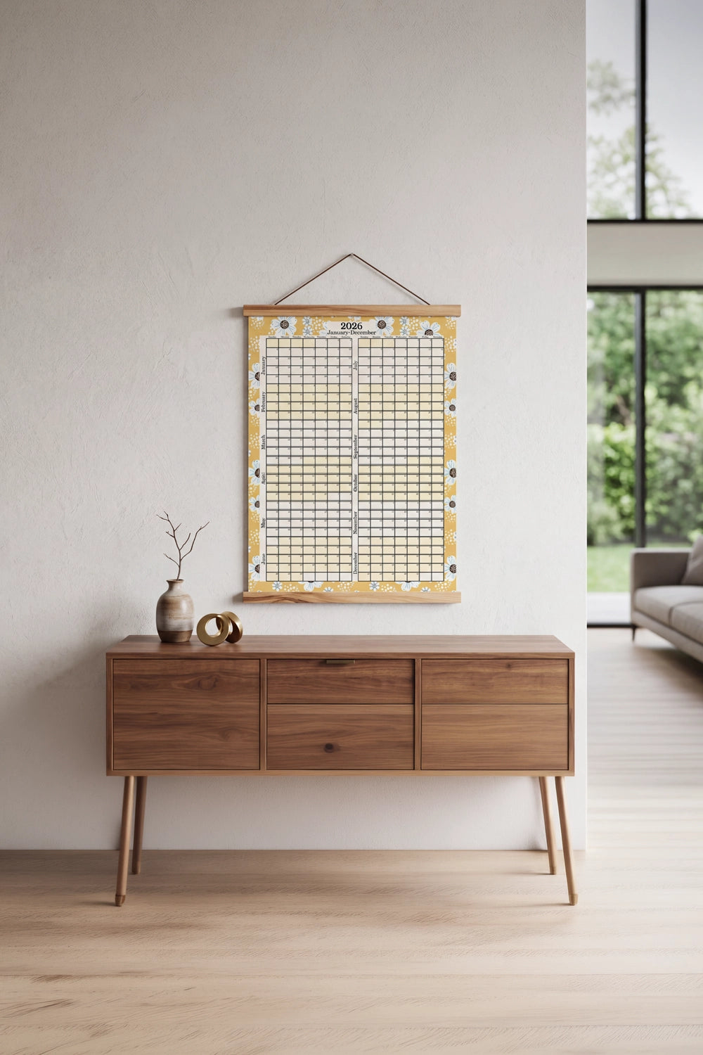 Wooden desk with decorative items against a light wall, featuring a large wall calendar.