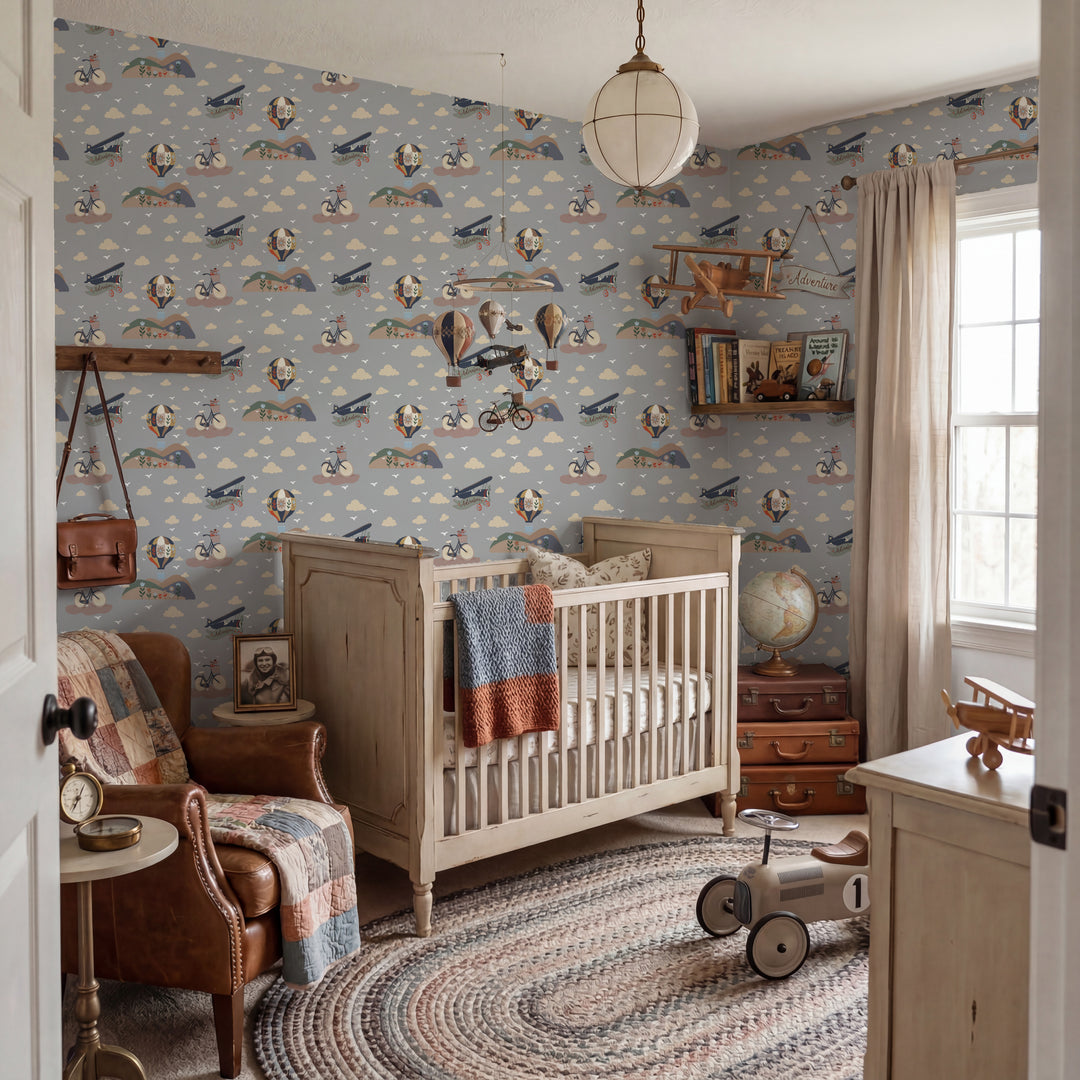 A styled nursery interior featuring light blue wallpaper with a vintage airplane and bicycle pattern, a white wooden crib, a brown leather armchair with a patchwork quilt, and a round braided area rug.