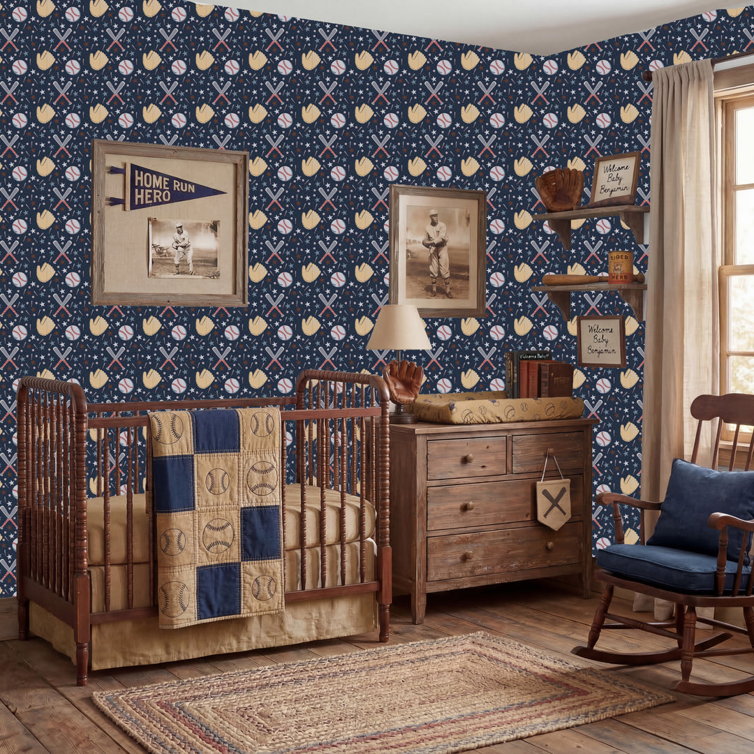 A styled nursery room featuring a navy blue wallpaper with a baseball-themed pattern of white bats, yellow baseballs, and white home plates. The room is furnished with a wooden crib, a wooden dresser, a rocking chair, and a patterned quilt.