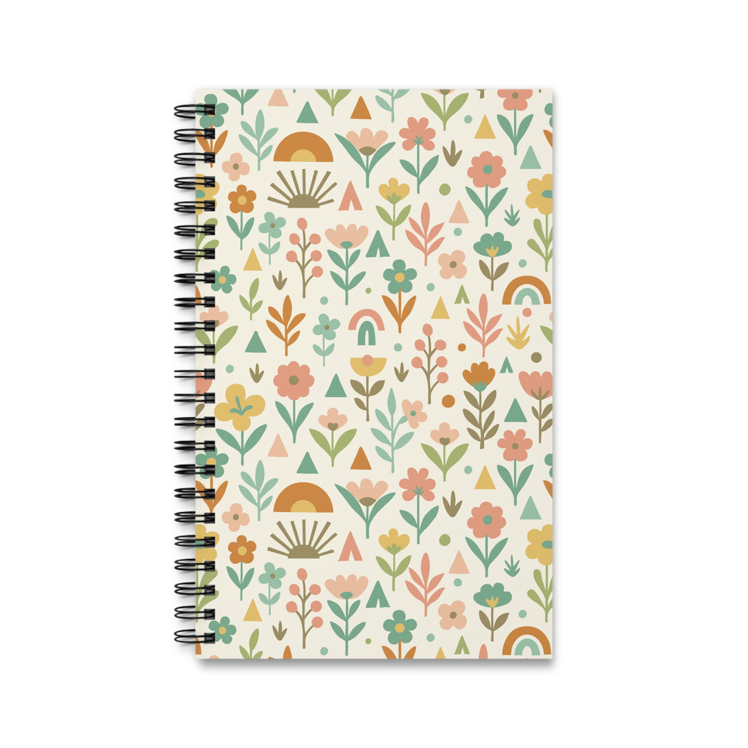 A spiral-bound notebook with a cream-colored cover decorated in a retro boho floral pattern featuring pink, orange, green, and yellow motifs, shown on a plain white background.