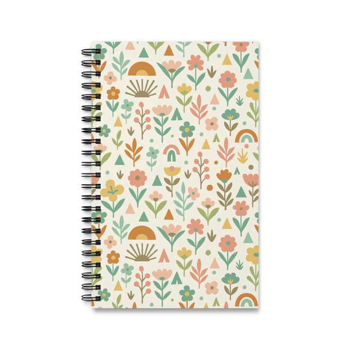 A spiral-bound notebook with a cream-colored cover decorated in a retro boho floral pattern featuring pink, orange, green, and yellow motifs, shown on a plain white background.