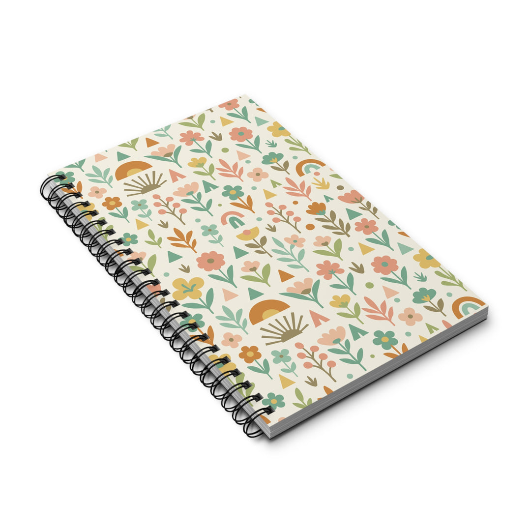 A spiral-bound notebook with a cream-colored cover decorated with a colorful, hand-drawn style botanical pattern of flowers, leaves, suns, and rainbows, shown on a clean white background.