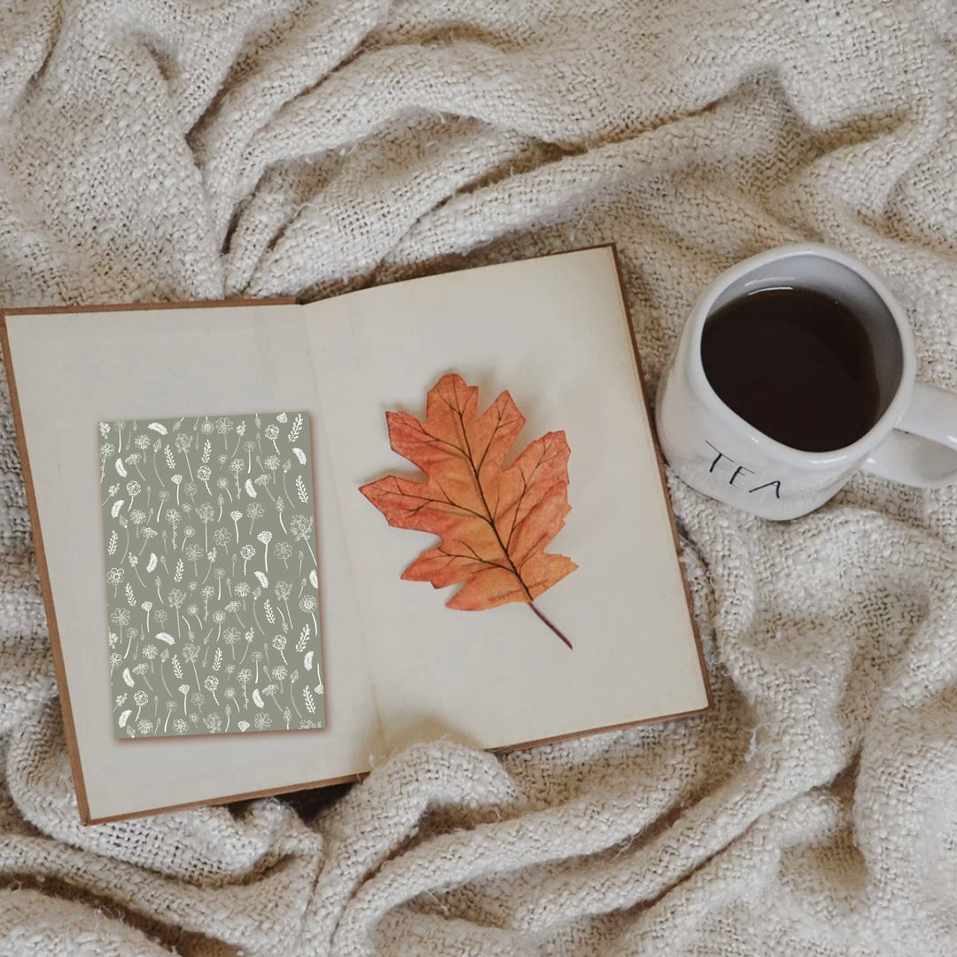 extra wide white traced flowers bookmark on book with leaf and drink