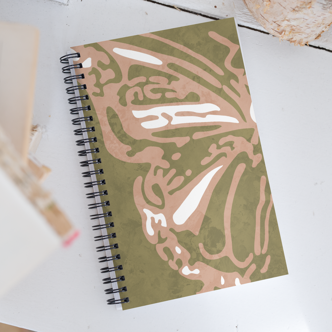 Picture of a green notebook with half of a coral colored butterfly with detailed wings.