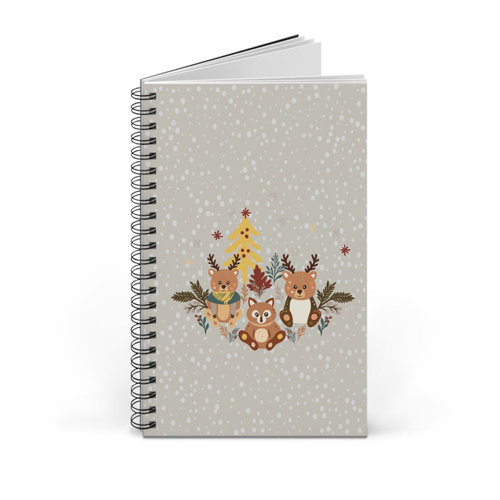 A spiral-bound notebook with a light gray cover decorated with a festive winter illustration of three woodland animals, a Christmas tree, and falling snowflakes.